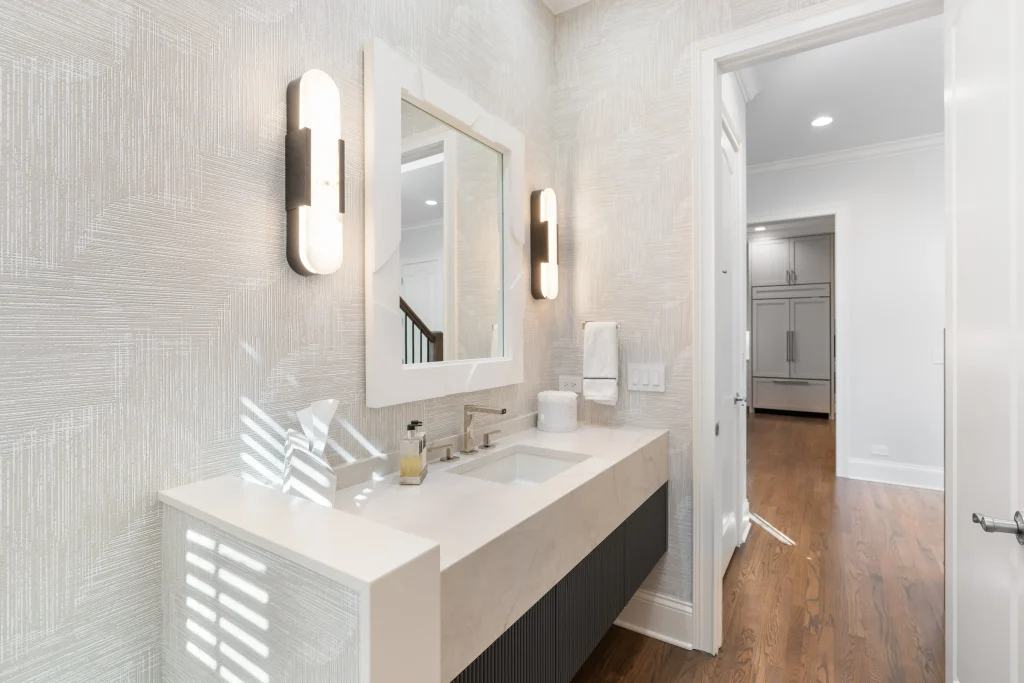 Modern bathroom featuring a white countertop with a sink and mirror, flanked by sleek wall lights