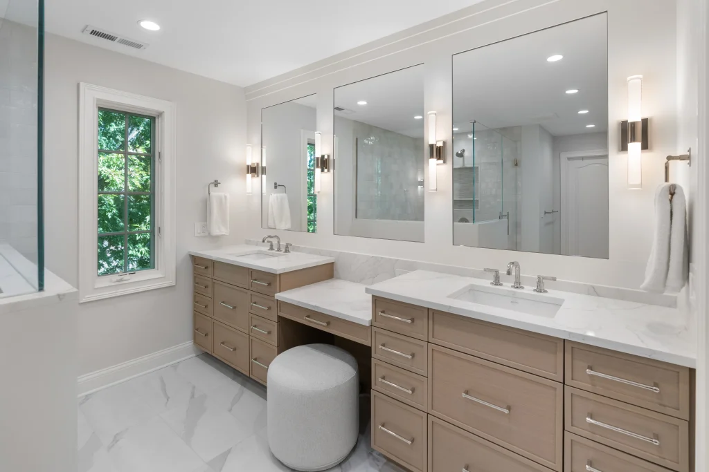 Bright, modern bathroom with dual sinks, marble countertops, and light wood cabinets