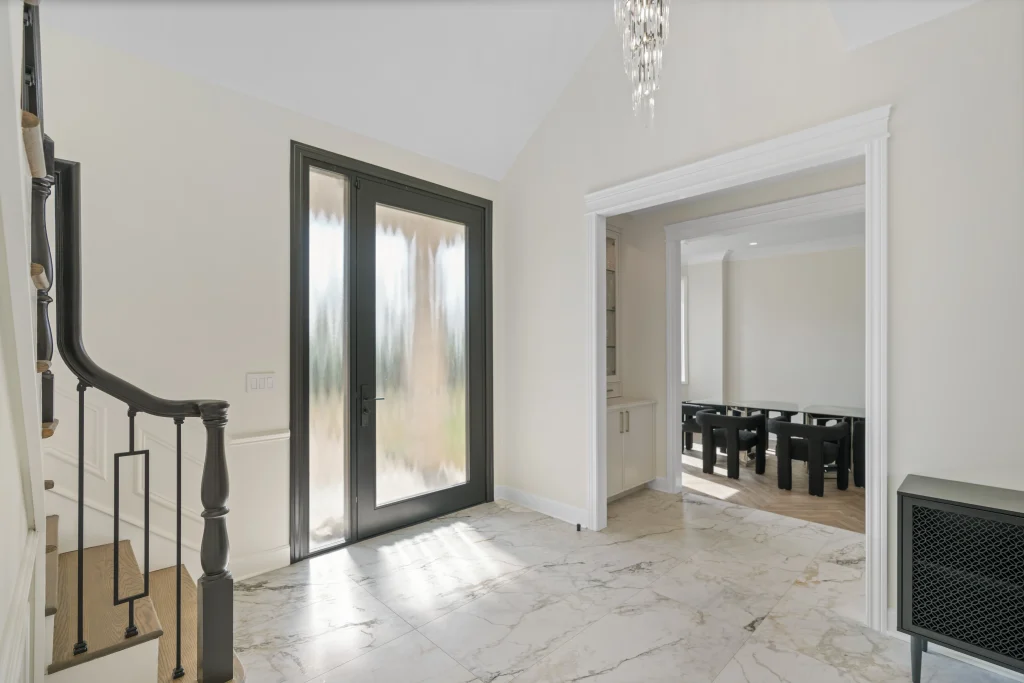 Bright foyer with large frosted glass door, marble floors, and a spiral staircase