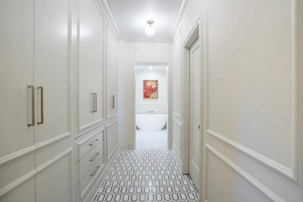 Narrow hallway with white paneled walls and geometric tile flooring