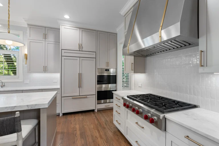 Modern kitchen with stainless steel appliances, including a large hood and range with red knobs