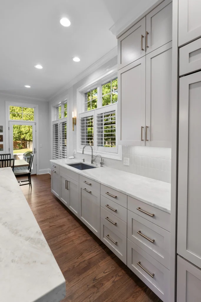 Bright, modern kitchen with white cabinets and marble countertops