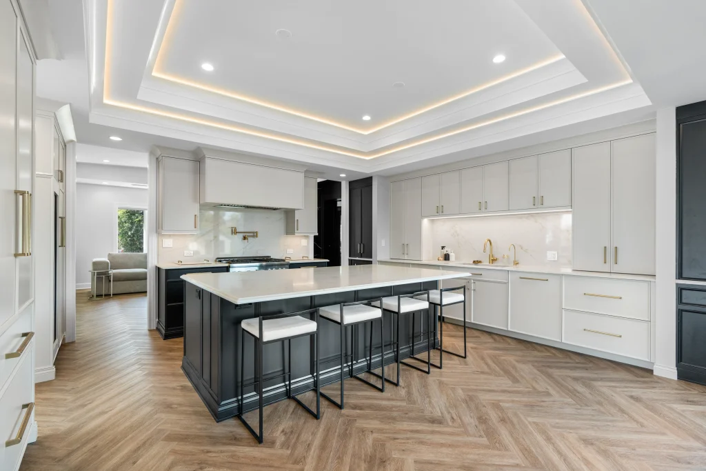 Modern kitchen with a large island, bar stools, sleek white cabinets, and herringbone wood floor