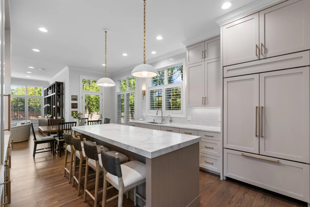 Spacious kitchen with light beige cabinets, marble island, and four chairs