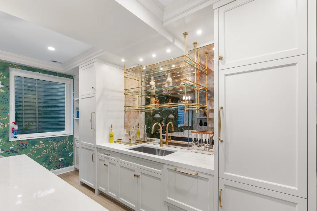 Elegant home sink area with white cabinets, gold accents, and a mirrored backsplash