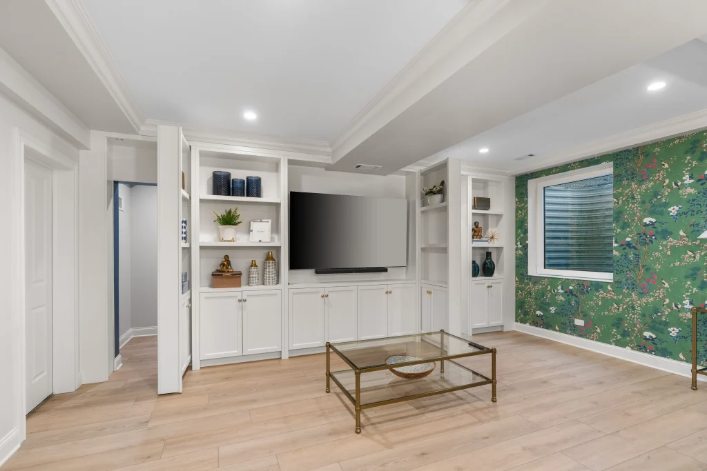 Modern living room with white built-in shelving, a large flat-screen TV, and decorative items