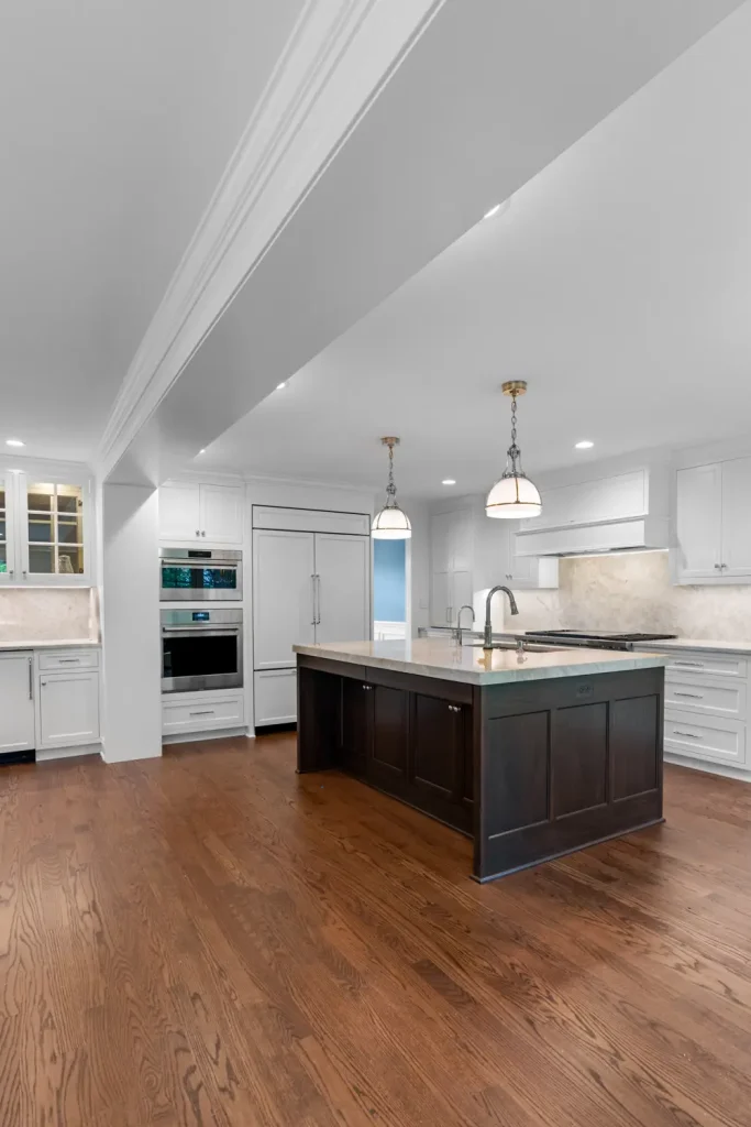 Spacious modern kitchen with white cabinets, stainless steel appliances, and a dark wood island