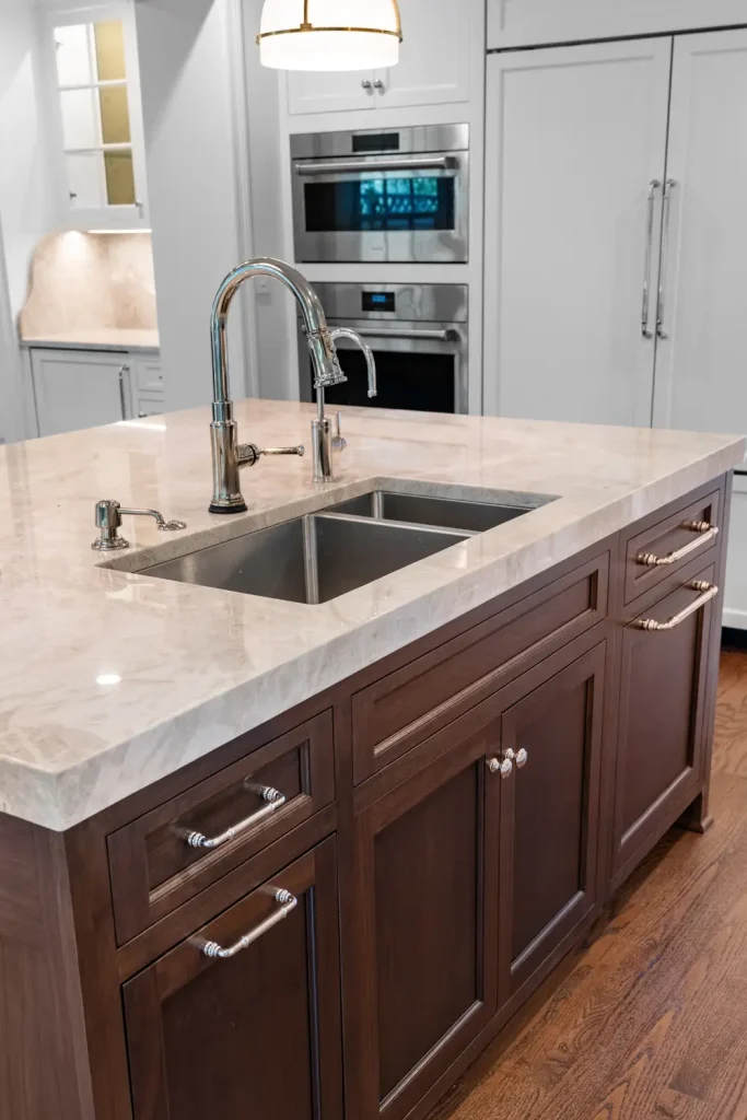 A modern kitchen island with a marble countertop and stainless steel sink