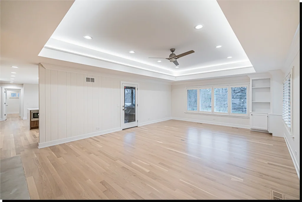 Bright, spacious living room with light wooden floors, recessed ceiling lights, and a modern ceiling fan