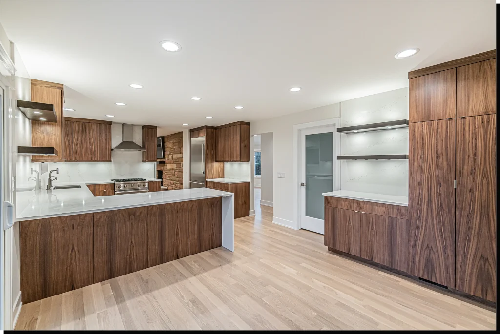 Modern kitchen with sleek wood cabinets and white countertops, featuring stainless steel appliances and recessed lighting