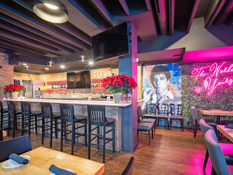 Modern restaurant interior with a bar, high chairs, and poinsettias