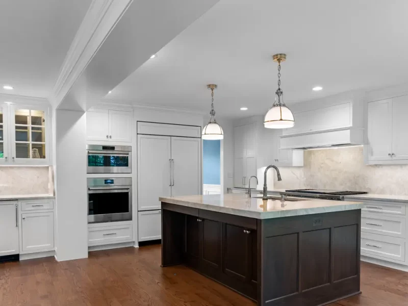 Spacious modern kitchen with white cabinets, stainless steel appliances, and a dark wood island